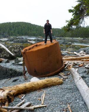 University of Alaska student Derek Chamberlin stands atop a large ship's mooring buoy which must have broken off it's chain anchor. The mooring buoy was found by NOAA marine debris scientists at Whale Bay, North Cape on Baranof Island during a recent marine debris survey of Southeast Alaska shores.