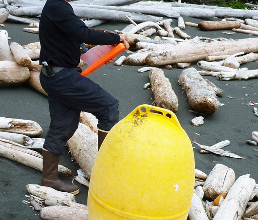 NOAA Marine Debris Program Deputy Director Jason Rolfe examines an unusual, large, yellow buoy found on the south side of Noyes Island, east of Cape Addington during a marine debris survey in Southeast Alaska
