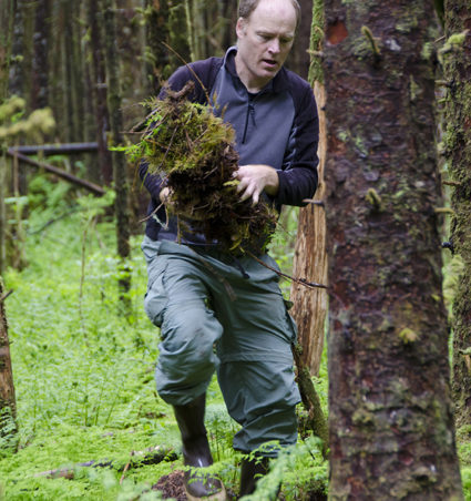 Volunteer John Hudson carries moss to the sides of the trail to re-vegetate muddy areas.