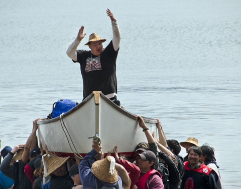 The group leader cheers as people carry the canoe ashore.