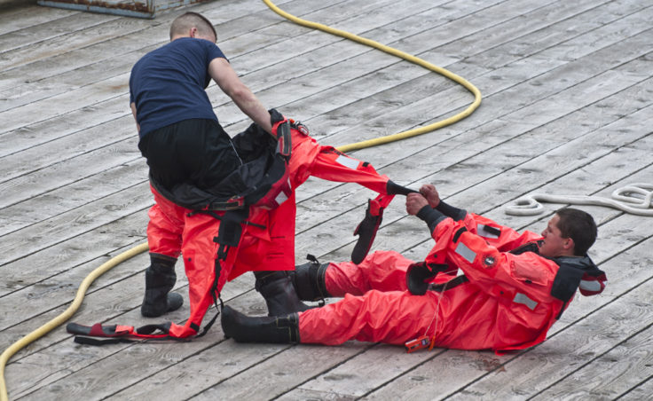 Teammates help each other remove the heavy survival suits following the swimming competition.