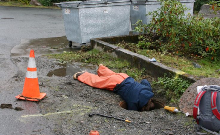 ADEC responder, Crystal Smith, checks manhole for potential pathways.