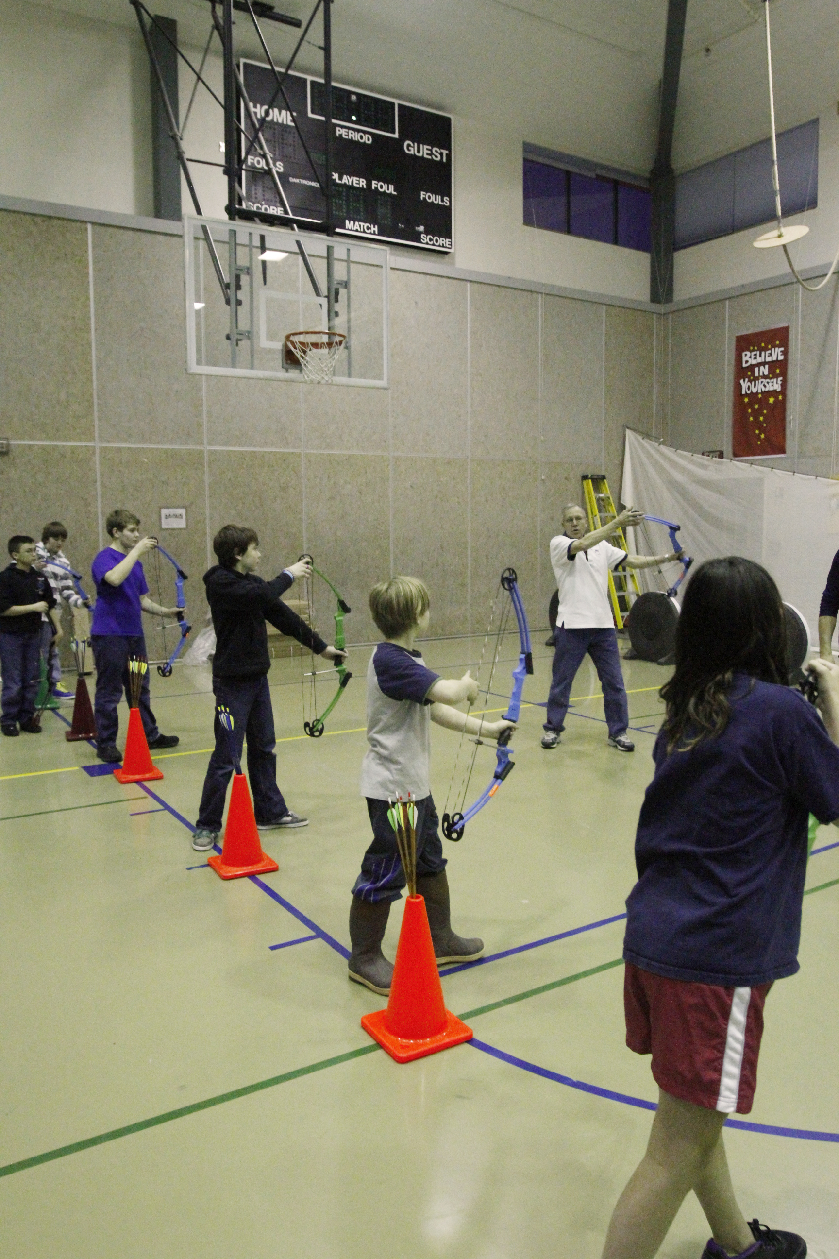 Students learn the proper way to hold an archery bow at Dzantik'i Heeni Middle School gymnasium.