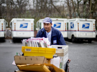 Veteran USPS letter carrier Michael McDonald gathers mail to load into his truck before making his delivery run in the East Atlanta neighborhood on Thursday, Feb. 7, 2013, in Atlanta. David Goldman/AP