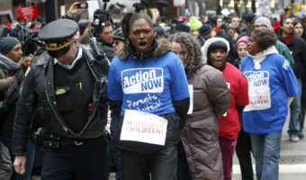 A Chicago police officer takes several protesters into custody on Wednesday, during an act of civil disobedience during a march and demonstration of opponents to a plan to close 54 Chicago Public Schools. Charles Rex Arbogast/AP