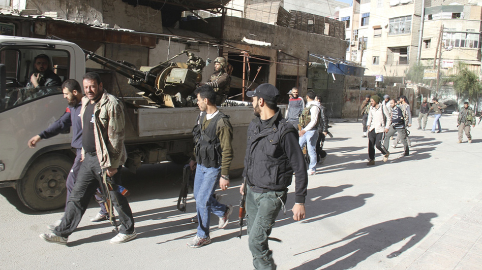 Rebels from the Free Syrian Army walk on a street in Damascus in this picture provided by Shaam News Network and taken March 23.