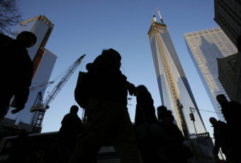 People pass the World Trade Center construction site in New York. Debris from the fallen towers will be sifted for victims' remains beginning Monday. Mark Lennihan/AP