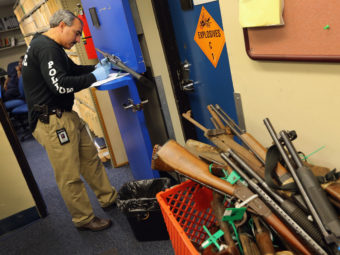 Detective Enrique Chavez logs weapons from a gun buyback in Miami. Arizona's new law requires municipalities to re-sell weapons recovered in such programs. Joe Raedle/Getty Images