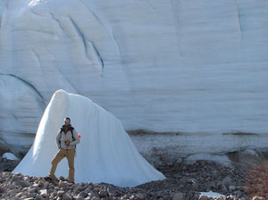 As the Teardrop Glacier on Ellesmere Island in the Canadian Arctic recedes, researchers have found a kind of evergreen plant called bryophytes coming out from beneath the ice. Here, a researcher stands next to part of the glacier for scale. Courtesy of Catherine La Farge