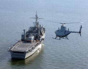 A U.S. Navy RQ-8A Fire Scout Vertical Takeoff and Landing Tactical Unmanned Aerial Vehicle (VTUAV) System prepares to land aboard the amphibious transport dock ship USS Nashville (LPD 13). This is the first autonomous landing of the Fire Scout aboard a Navy vessel at sea. With an on-station endurance of over four hours, the Fire Scout system is capable of continuous operations, providing coverage at 110 nautical miles from the launch site. Utilizing a baseline payload that includes electro-optical/infrared sensors and a laser rangefinder/designator, Fire Scout can find and identify tactical targets, track and designate targets, accurately provide targeting data to strike platforms, employ precision weapons, and perform battle damage assessment.