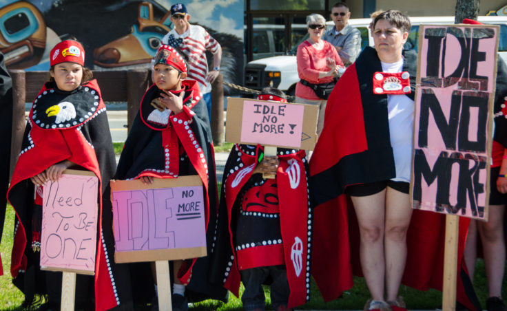 Dancers hold signs while watch a speech at the rally. (Photo by Heather Bryant/KTOO)