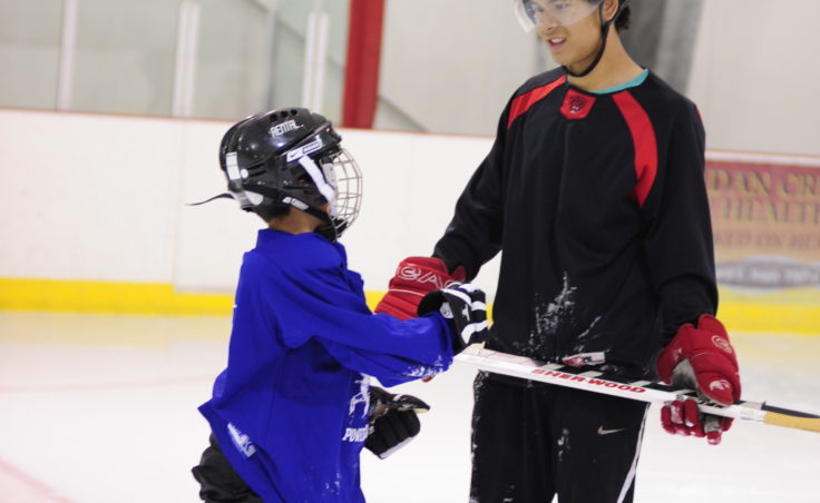 Former Juneau Douglas High standout Tod Baseden spends time with a boy who wants to learn how to play hockey Saturday at Treadwell Ice Arena.