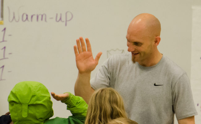 Peter Nestler high fives students on their way out of the gym.