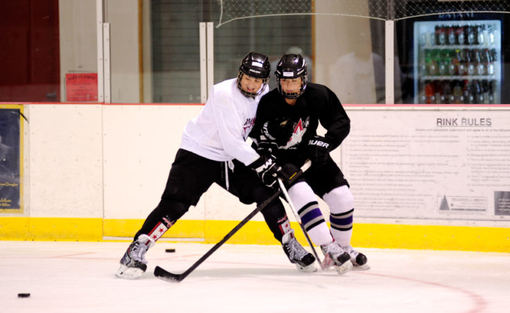 Emma Kaelke and Gavin Murhpy battle for the puck while attending the Rocky Mountain Hockey School at Treadwell Ice Arena.