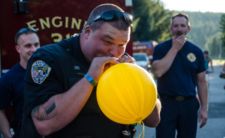 Officer Steve Warnaca blows up a balloon for kids at the block part