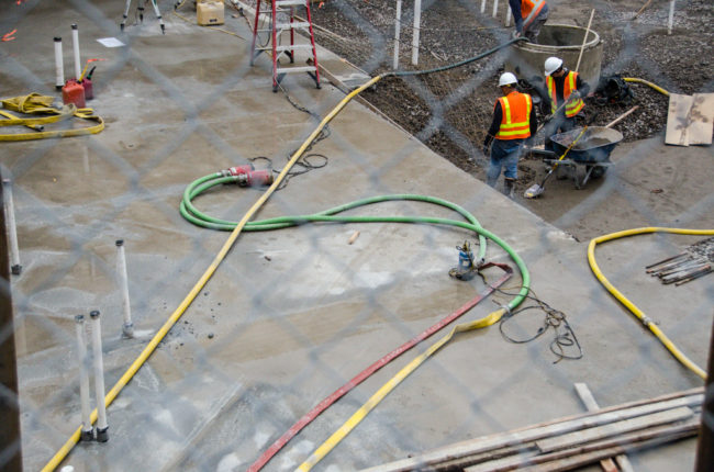 Pumps and hoses are spread throughout the construction site to deal with excess water. 