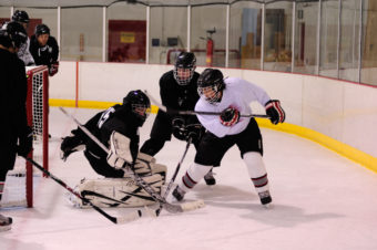 Shane Moller (white) and Grant Ainsworth mix it up in front of the net during a small-area drill led by Juneau’s Matt Boline.