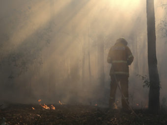Flames flicker near Bilpin, Australia, as a firefighter finishes securing the area on Wednesday. Rob Griffith/AP