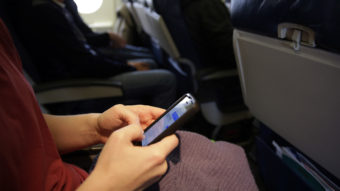 The new head of the Federal Communications Commission proposes allowing airline passengers to make phone calls during flights. Here, a passenger looks at her cellphone before a flight last month. Matt Slocum/AP