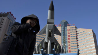 Concerns over China's air defense claims led Secretary of Defense Chuck Hagel to call Japan's defense minister Wednesday. Here, a man makes a call near a replica of a Chinese fighter jet displayed in Beijing Wednesday. Ng Han Guan/AP
