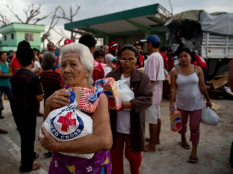 An elderly woman and others leave after getting some help from Red Cross volunteers Monday in Dagami, the Philippines, about 20 miles south of the city of Tacloban. Millions of people need assistance because their homes were destroyed by Typhoon Haiyan on Nov. 8. Odd Andersen /AFP/Getty Images