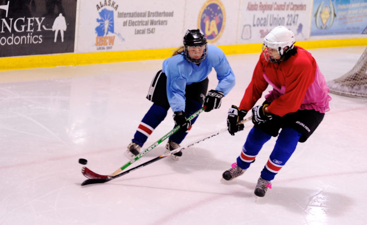 Caroline Schultz (blue) and Emily Hutchison battle for the puck to the left of the net during the 10th Annual Jamboree women’s hockey tournament at Treadwell Ice Arena.