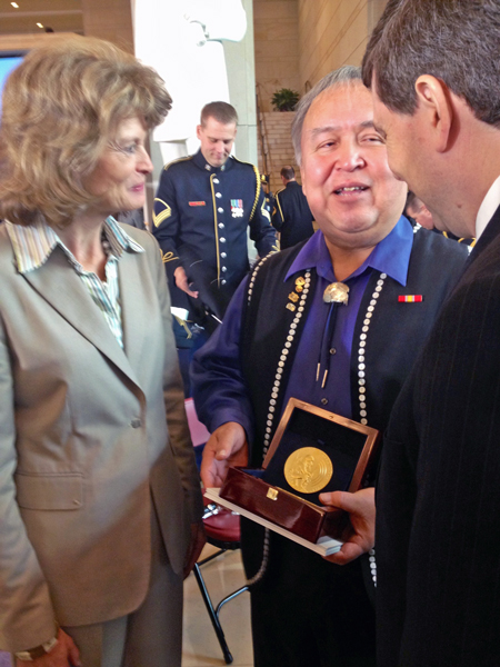 Ozzie Sheakley hold the Congressional Gold Medal awarded to the Tlingit Tribe for code talking service during World War II. He speaks to Sens. Lisa Murkowski and Mark Begich after the ceremony. Photo by Liz Ruskin, APRN – Washington DC.