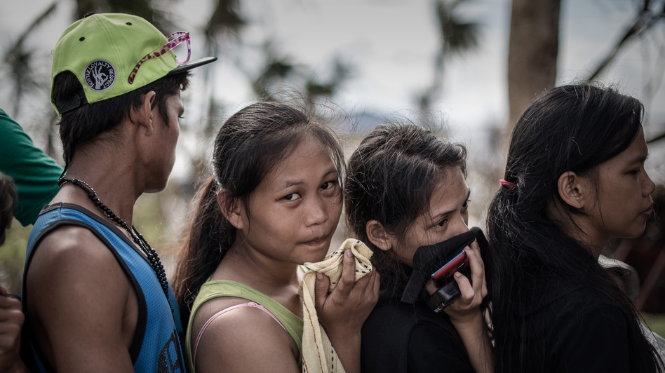 In Tacloban, the Philippines, on Thursday, some survivors waiting in a line to charge cellphones covered their faces because of the lingering smell of dead bodies. Philippe Lopez /AFP/Getty Images