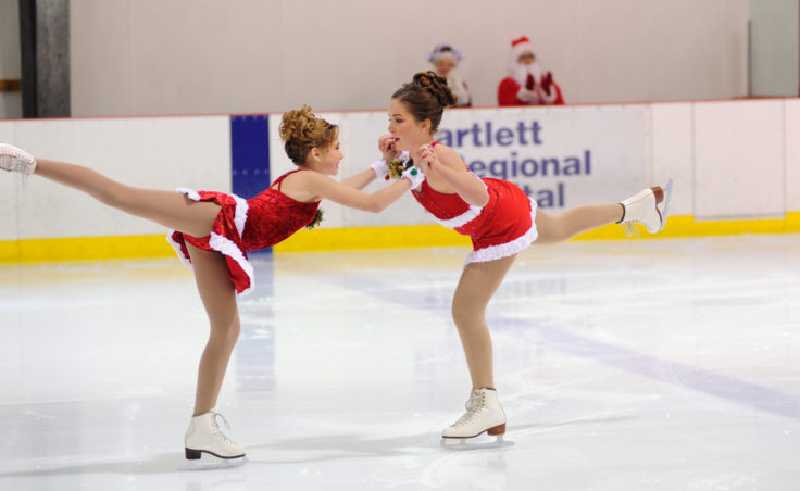 Grace Walli and Katie McKenna close out their routine with Santa and Mrs. Claus applauding in the backdrop during Juneau Skating Club’s annual holiday recital.