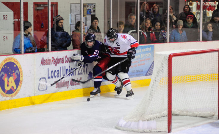 Juneau center Grant Ainsworth pins North Pole’s James Laszoffy along the boards, looking to maintain possession of the puck during the two-game series at Treadwell Ice Arena.