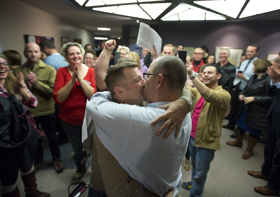 Chris Serrano, left, and Clifton Webb kiss after being married, as people wait in line to get licenses outside of the marriage division of the Salt Lake County Clerk's Office in Salt Lake City on Friday. Kim Raff/AP