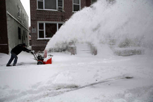 A man clears snow from a sidewalk in Brooklyn following a snow storm that left up to seven inches of snow on Friday. A major snowstorm producing blizzard-like conditions brought bone-chilling temperatures and high winds to the Northeast, with nearly 2 feet of snow falling in some areas of Massachusetts.  (Spencer Platt/Getty Images)