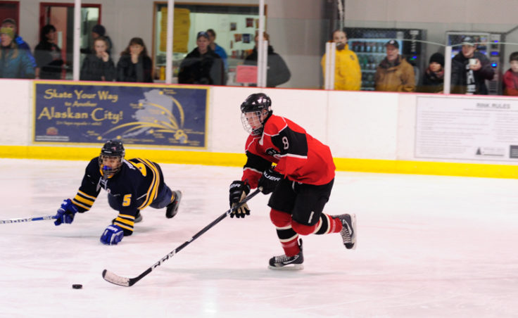 Juneau’s Zach Hebert rushes in on Bartlett goalie Felix Malakye while skating past Bartlett’s Raphael Turner during the weekend series at Treadwell Ice Arena.