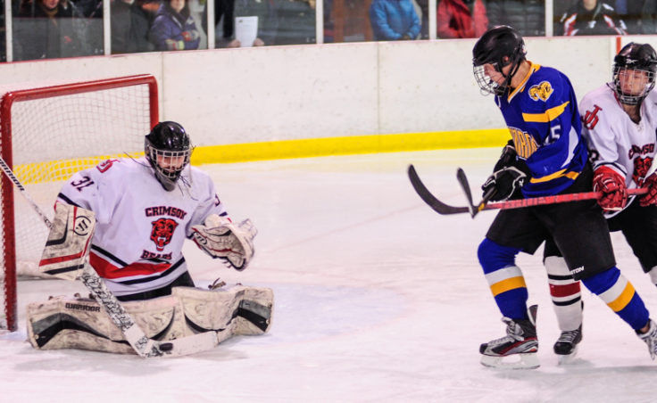Juneau goalie Neal Chapman gets the call for Saturday night’s game and turns aside this shot with teammate Michael Dale holding off Monroe Catholic’s Grand Olson.