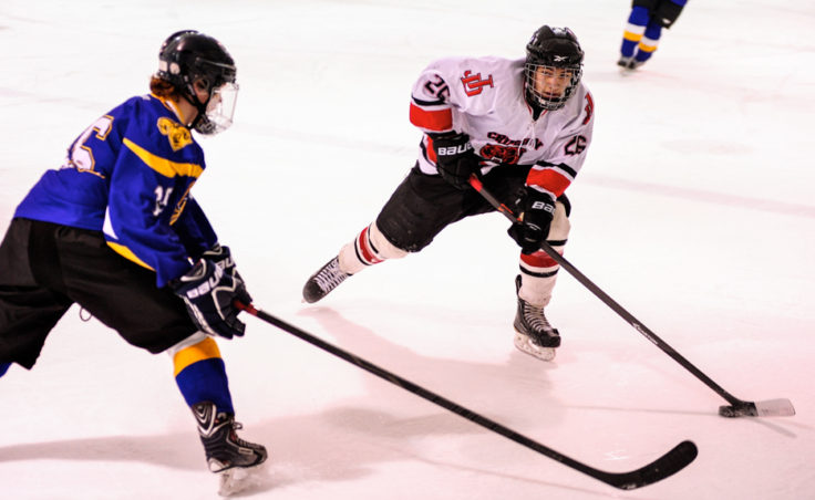 Juneau’s Josh Lahnum skates in on Monroe Catholic’s Dylan Steele during Juneau’s weekend series at Treadwell Ice Arena.