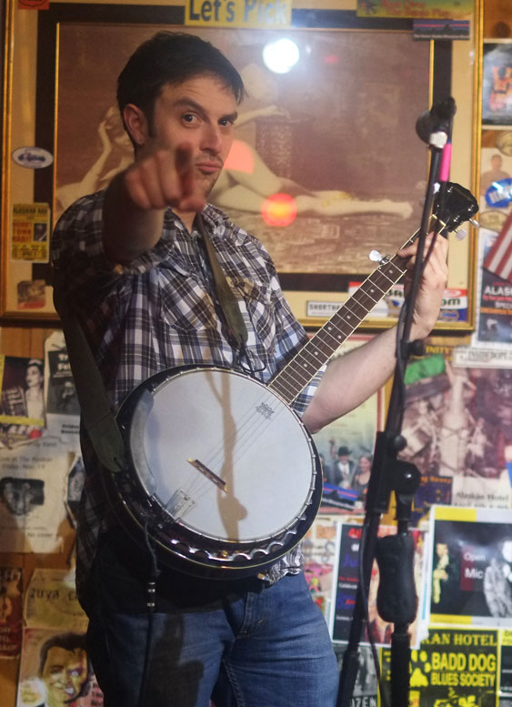 Man pointing onstage at Alaskan with banjo