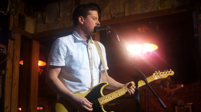 Morgan Deering playing guitar onstage at the Alaskan