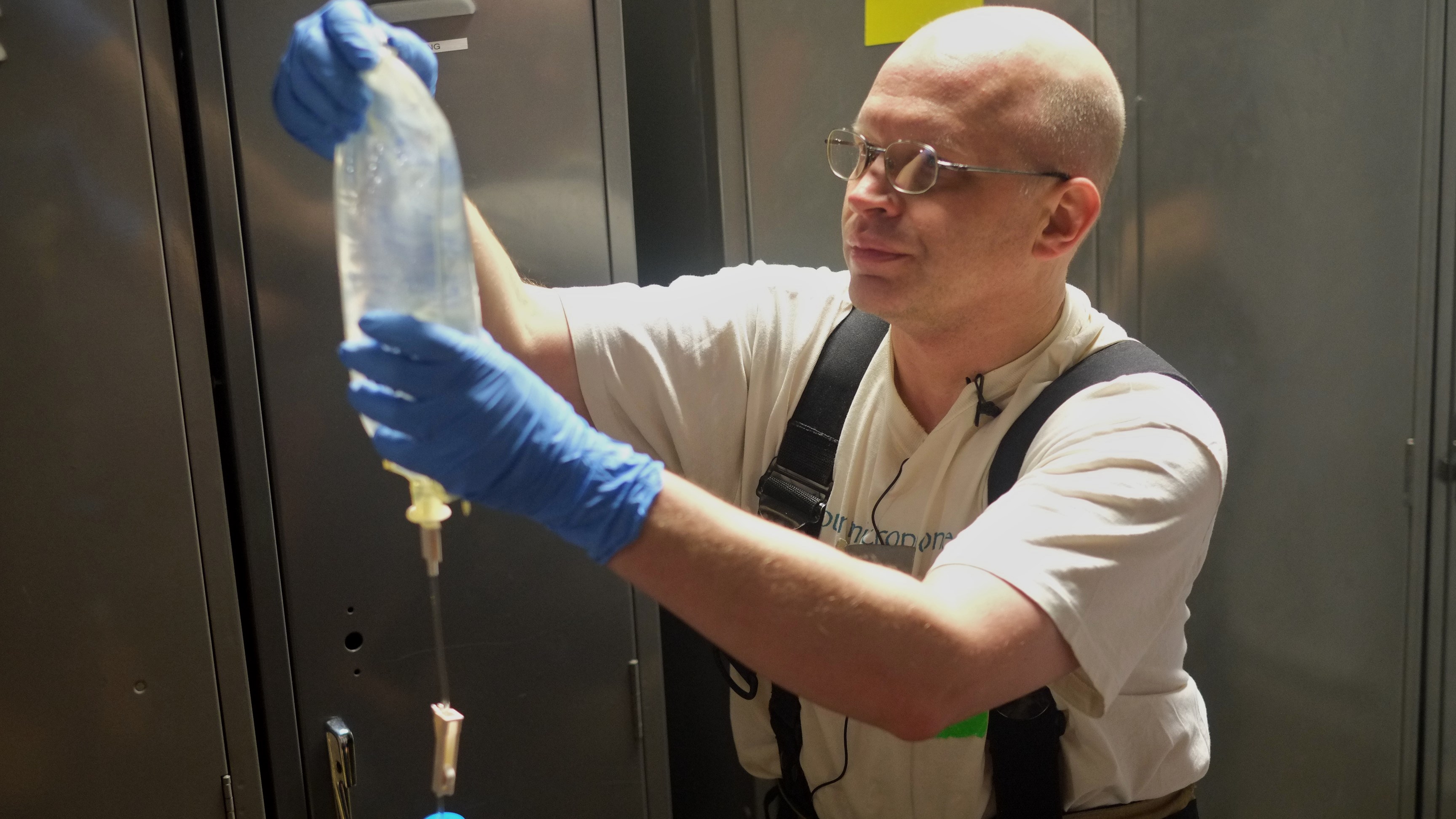 KTOO's Matt Miller checks an intravenous solution during the EMT exercise at a recent Fire Ops 101 training exercise in Juneau. (Photo by Annie Bartholomew/KTOO)