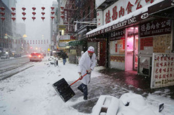 A man clears snow in front of DC Meat Market in the Chinatown neighborhood of New York City on Thursday. Snow and sleet are falling along the East Coast, from North Carolina to New England, a day after sleet, snow and ice bombarded the Southeast. Mark Lennihan/AP