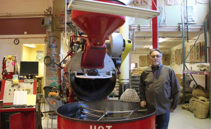 Heritage Coffee Roasting Co. founder Grady Saunders stands in front of the company's roaster, which once belonged to Starbucks Coffee Co. (Photo by Lisa Phu/KTOO)