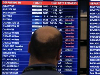 A man looks at a flight departure board filled with weather-related cancellations and delays at Boston's Logan Airport in January. Charles Krupa/AP