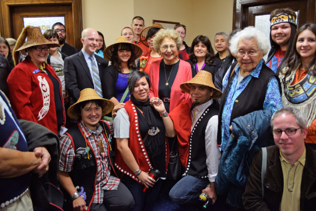 Rep. Jonathan Kreiss-Tomkins (in suit coat and blue shirt) and supporters of House Bill 216 gather in a Capitol hallway for a group photo to celebrate passage of the bill through the House State Affairs Committee, April 1, 2014. The bill would symbolically make 20 Alaska Native languages official state languages alongside English. (Photo by Skip Gray/Gavel Alaska)