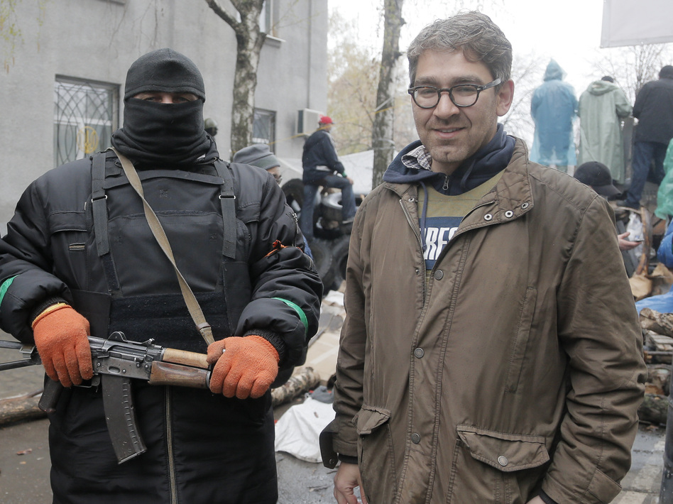 In a photo taken earlier this month, U.S. reporter Simon Ostrovsky stands with a pro-Russian gunman at a seized police station in the eastern Ukrainian town of Slovyansk. Ostrovsky has reportedly been seized by the pro-Russian insurgents. (Efrem Lukatsky/AP)