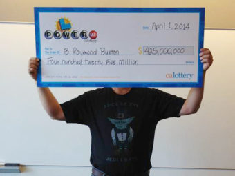 Hidden, he is: This photo provided by the California Lottery shows Powerball winner B. Raymond Buxton holding his ceremonial check. The big winner is trying to keep his life private. He showed up in a T-shirt that says "Luck of the Jedi, I Have." California Lottery/AP