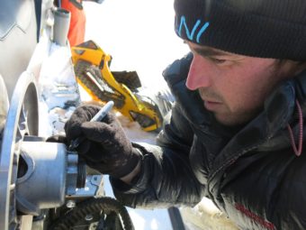 Ben Jones of the USGS Alaska Science Center in Anchorage works on a broken snowmachine on a frozen lake not far from the Arctic Ocean. (Photo by Ned Rozell)