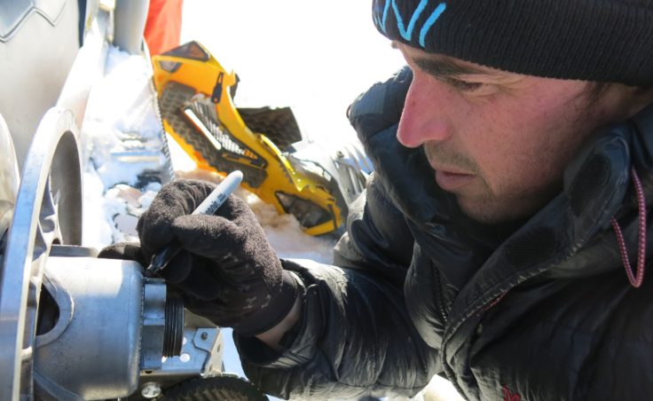 Ben Jones of the USGS Alaska Science Center in Anchorage works on a broken snowmachine on a frozen lake not far from the Arctic Ocean. (Photo by Ned Rozell)