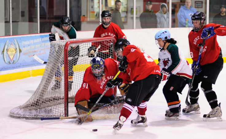 Killer Whales’ Becca Parks looks to clear the puck from the crowd gathering in front of goalie Jason Soza.