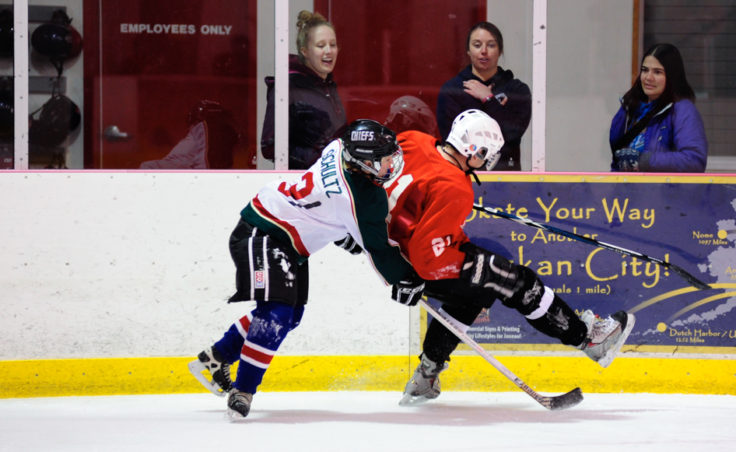 Funter Bay’s Caroline Schultz nearly upends Killer Whales’ Mike Cooney as they go for the puck along the boards.