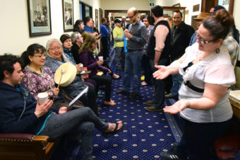 Irene Lampe drums while Ricky Tagabon (to her right) and Della Cheney (to her left) sing while Jessica Dominy dances in traditional Tlingit style in the second floor hallway of the Alaska State Capitol, April 21, 2014. They were a few of the one hundred or so supporters of House Bill 216 that gathered on April 21, 2014, and stayed until 3am the next day waiting for the Senate to pass the bill that makes 20 Alaska Native languages official state languages alongside English. (Photo by Skip Gray/Gavel Alaska)