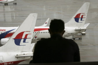 A visitor looks out from the viewing gallery as Malaysia Airlines aircraft sit on the tarmac at the Kuala Lumpur International Airport (KLIA) in Sepang, Malaysia, on May 27, 2014. Vincent Thian/AP